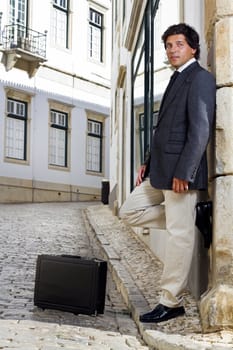 View of a happy business man with a black suitcase on a European city.