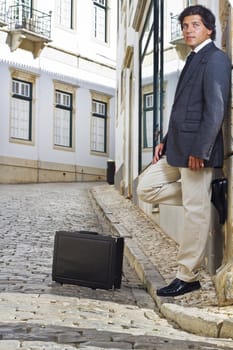 View of a happy business man with a black suitcase on a European city.