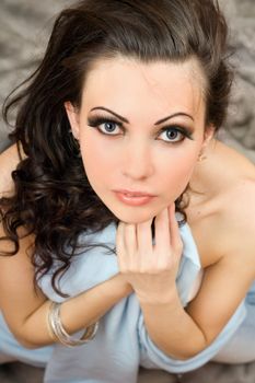 Perfect young brunette sitting on grey fur