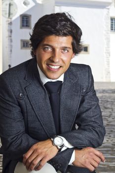 View of a happy business man with a black suitcase on a European city.