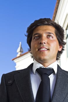 View of a happy business man with a black suitcase on a European city.