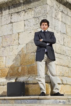 View of a happy business man with a black suitcase on a European city.