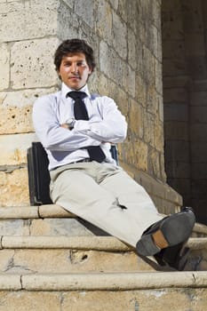 View of a happy business man with a black suitcase on a European city.