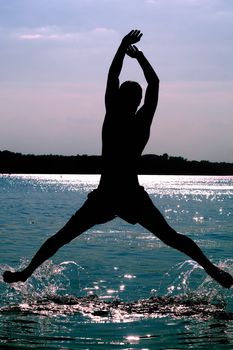 Silhouette of a man jumping in the river