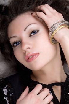 Portrait of the beautiful lady lying on grey fur coat