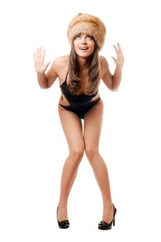 Playful brunette wearing black swimsuit and fur-cap. Isolated on white