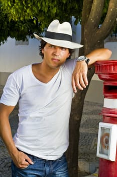 View of a handsome man with white shirt and hat on a urban city.