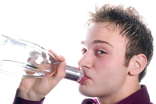 The young man drinks vodka from a bottle. Isolated