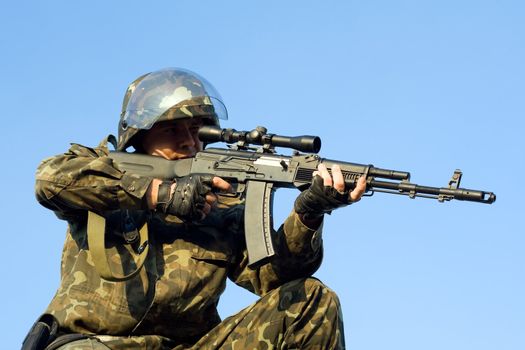 Sniper in camouflage uniform aiming his machine gun