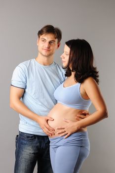 Happy pregnant couple over grey background