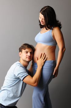 Happy pregnant couple over grey background