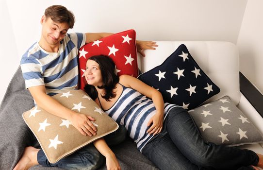 Happy pregnant couple on a sofa