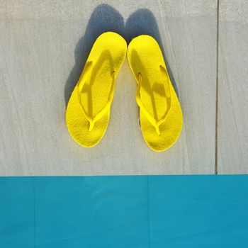 Yellow sandals by a swimming pool 