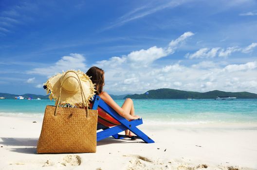 Girl on a tropical beach in chaise lounge