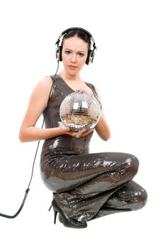Attractive young brunette in headphones with a mirror ball. Isolated on white