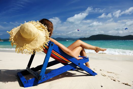 Girl on a tropical beach in chaise lounge