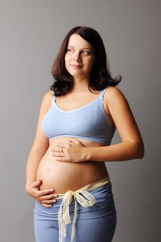 Portrait of a pregnant woman touching her belly with hands