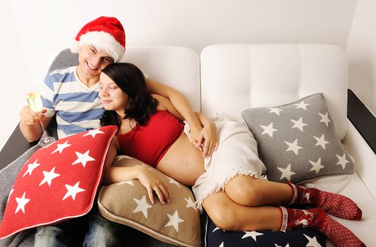 Happy pregnant couple at christmas on a sofa