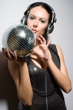 Portrait of attractive young brunette in headphones with a mirror ball
