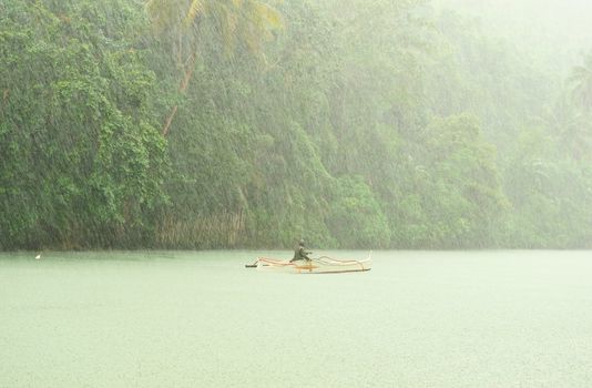 Tropical rain above river running through rainforest