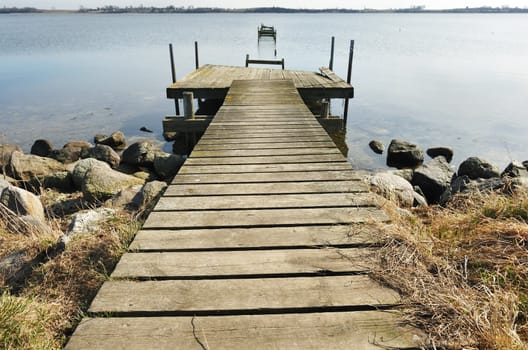 Old jetty wooden walkway pier on the lake