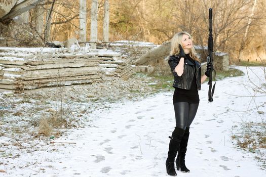 Attractive young woman with a gun outdoors