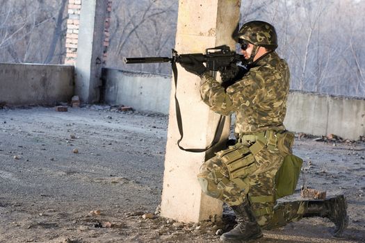 Armed man on his knees aiming at the abandoned building