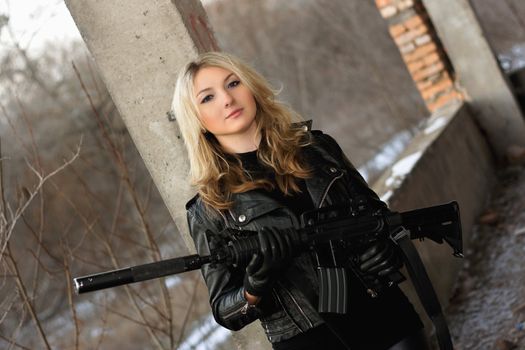 Beautiful young woman with a rifle  in neglected building