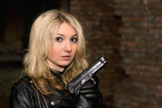 Scared beautiful woman with a gun in abandoned house