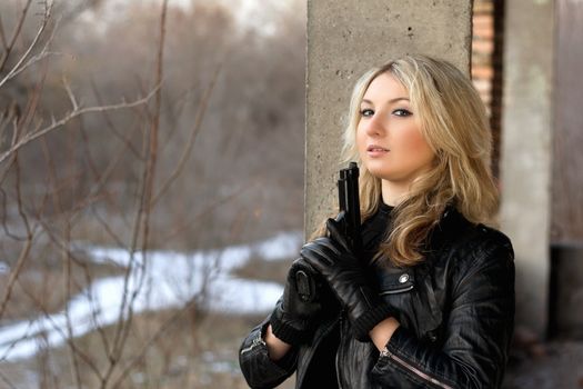 Cute girl in leather jacket holding a gun