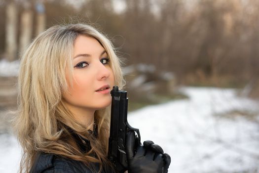 Hot girl holding a gun in winter forest