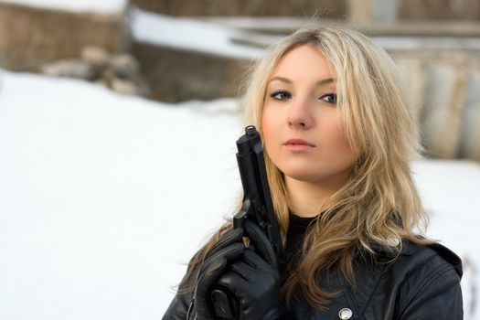 Hot girl holding a gun against the snow