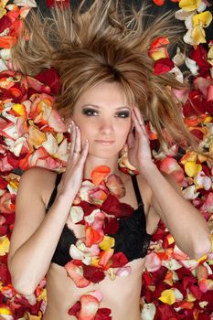 Portrait of attractive blonde lying in rose petals