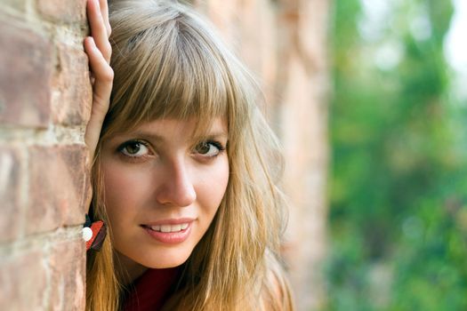 Portrait of young blond woman near the brick wall