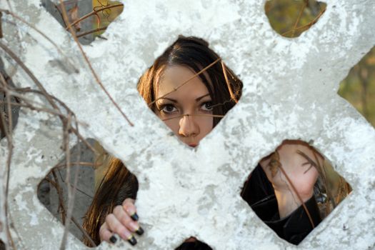 The scared young woman looks through a fence