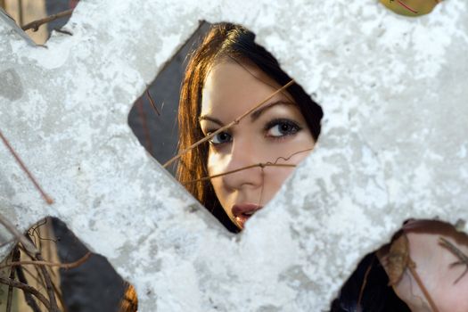 The young woman looks through a fence