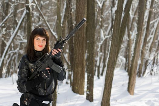 Portrait of sexy young woman with a rifle in forest