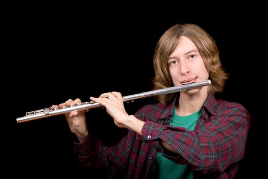 The young man plays a flute over black