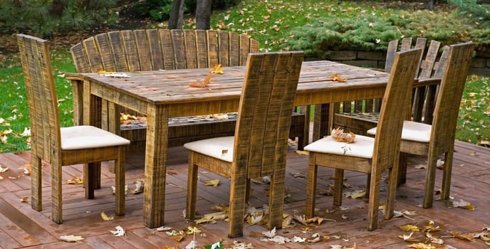 Abscissed leaves of maple on a table and chairs among a green grass