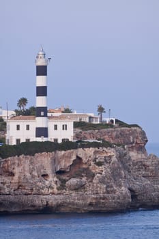white lighthouse on rocks in the sea ocean water sky blue summer