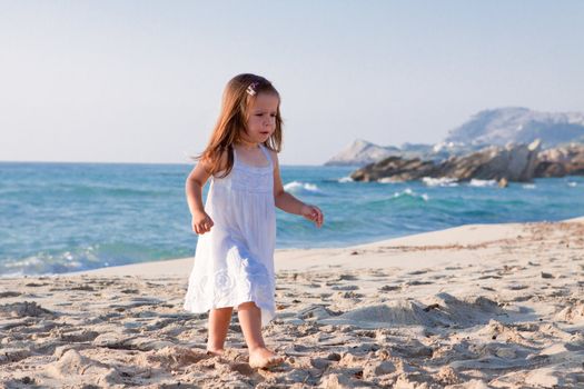 little cute girl smiling playing on beach in summer vacation