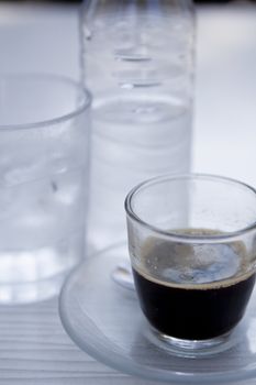 hot aromatic espresso cup and cold water in glass in a caf� in summer outdoor