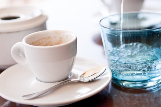 hot aromatic espresso cup and cold water in glass in a caf� in summer outdoor