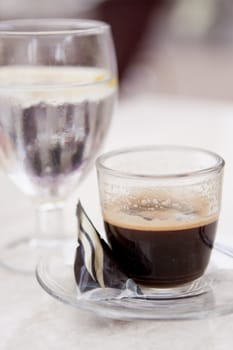 hot aromatic espresso cup and cold water in glass in a caf� in summer outdoor