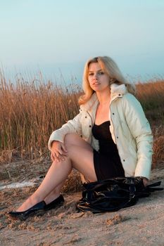 Girl sitting on the beach in the light of setting sun