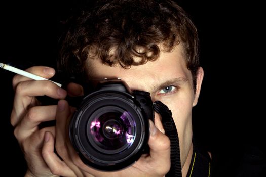 The young man - photographer behind work. Isolated on a black background 4