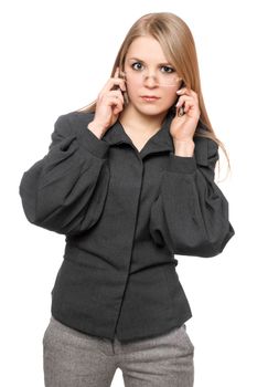 Portrait of discontented young blonde in a gray business suit with two phones