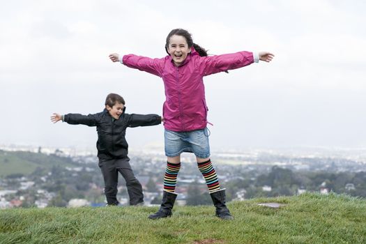 Two children playing in super strong wind, on top of Mount Eden, Auckland, New Zealand.