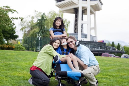 Disabled boy in wheelchair surrounded by family, outdoors by the Space Needle in Seattle