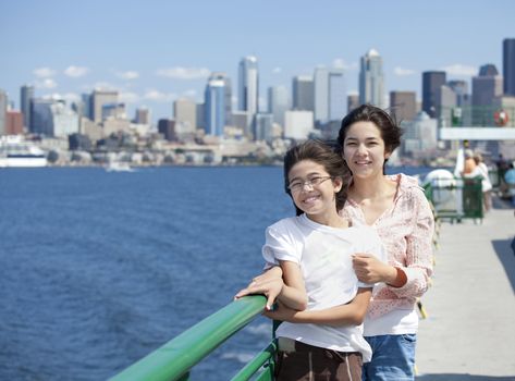 Two sisters on windy ferry deck with Seattle skyline in background